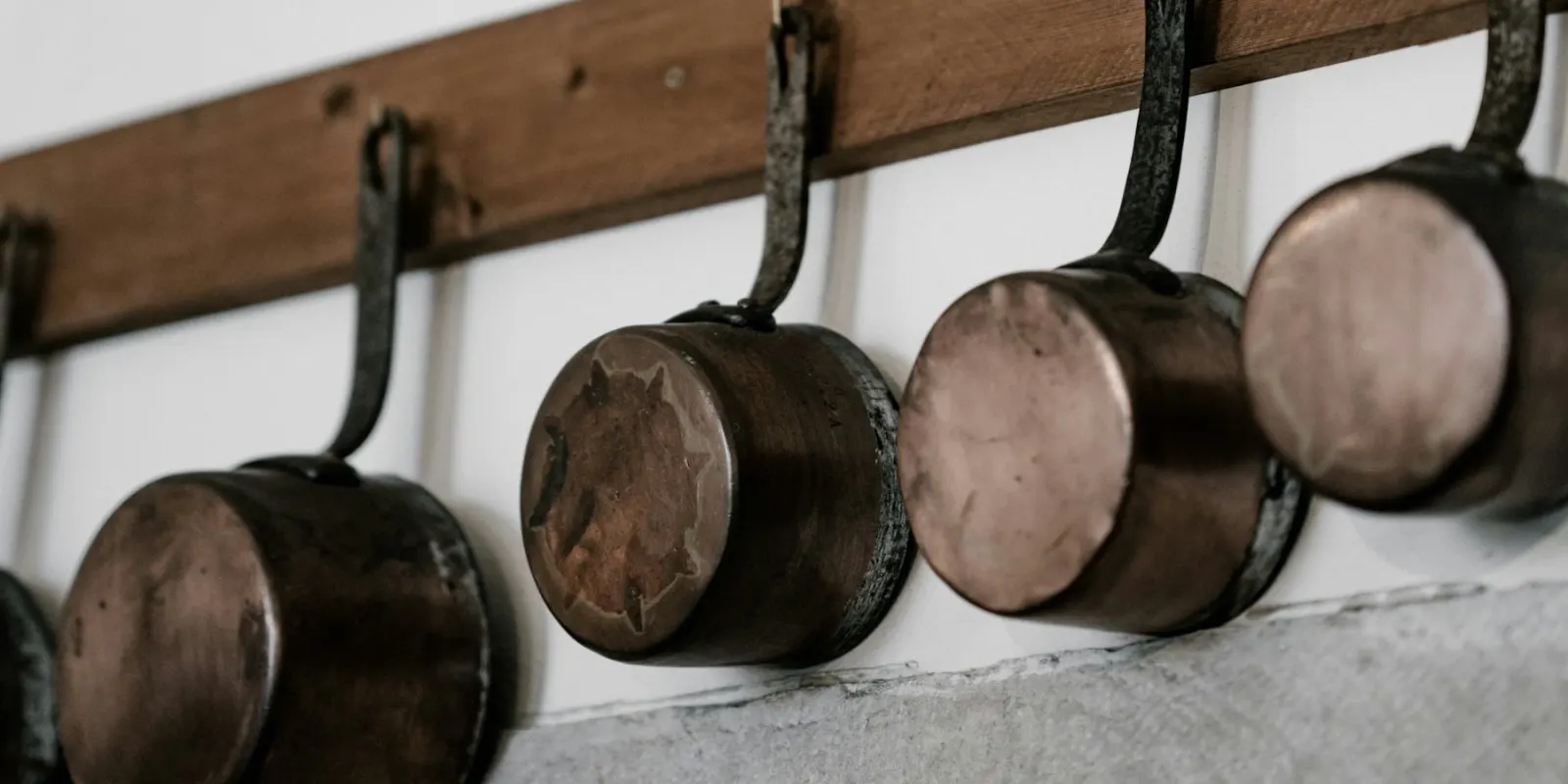 Pans hanging from a rail on a kitchen wall